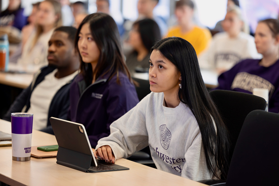 Students in purple NU sweatshirts observing a lecture