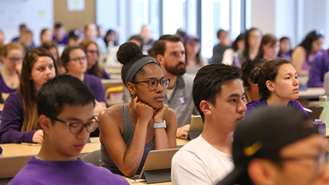 Students learning in a lecture hall wearing Northwestern purple.