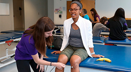 a student practicing a knee tap exam on another student