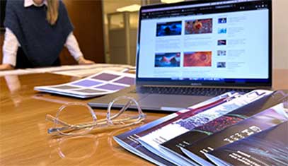 A laptop and magazines atop a desk