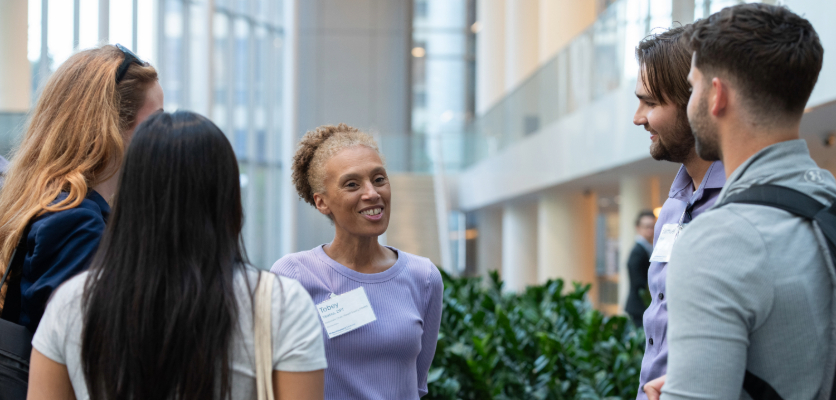 A speaker engages in conversation with four students, sharing insights and guidance