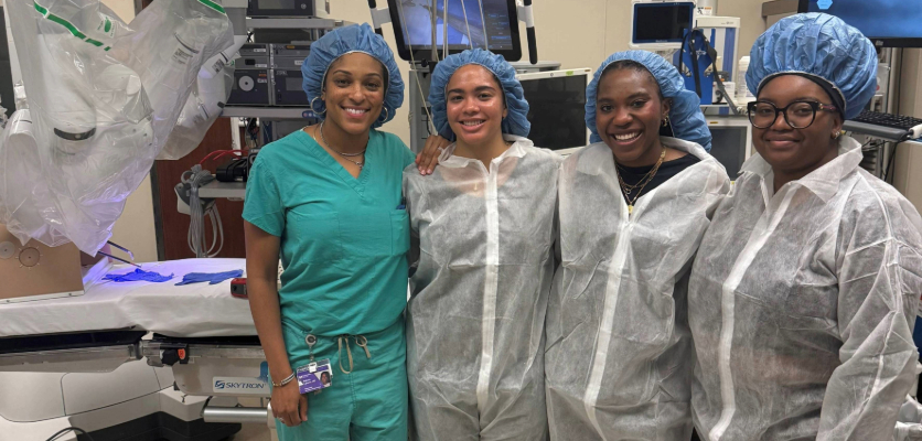 Four women in scrubs in front of machinery