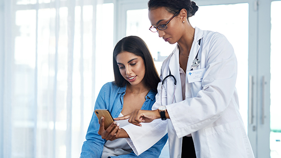 A doctor points something out to a patient on their iPhone