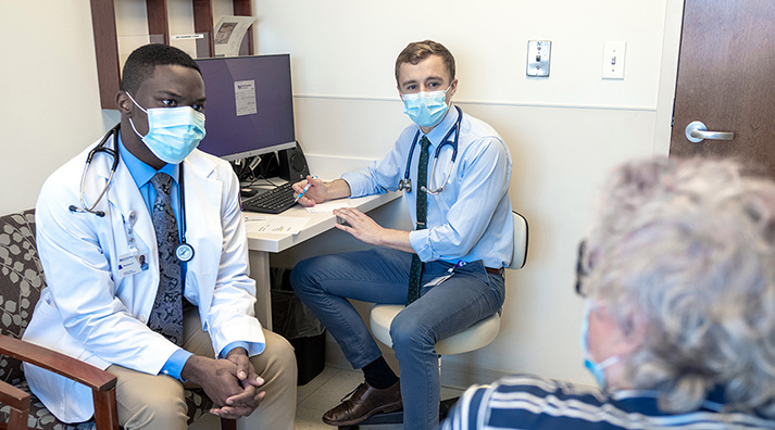 Two young doctors talking to a patient in a clinical setting