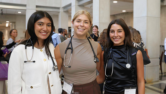 Three medical students with stethoscopes smiling 