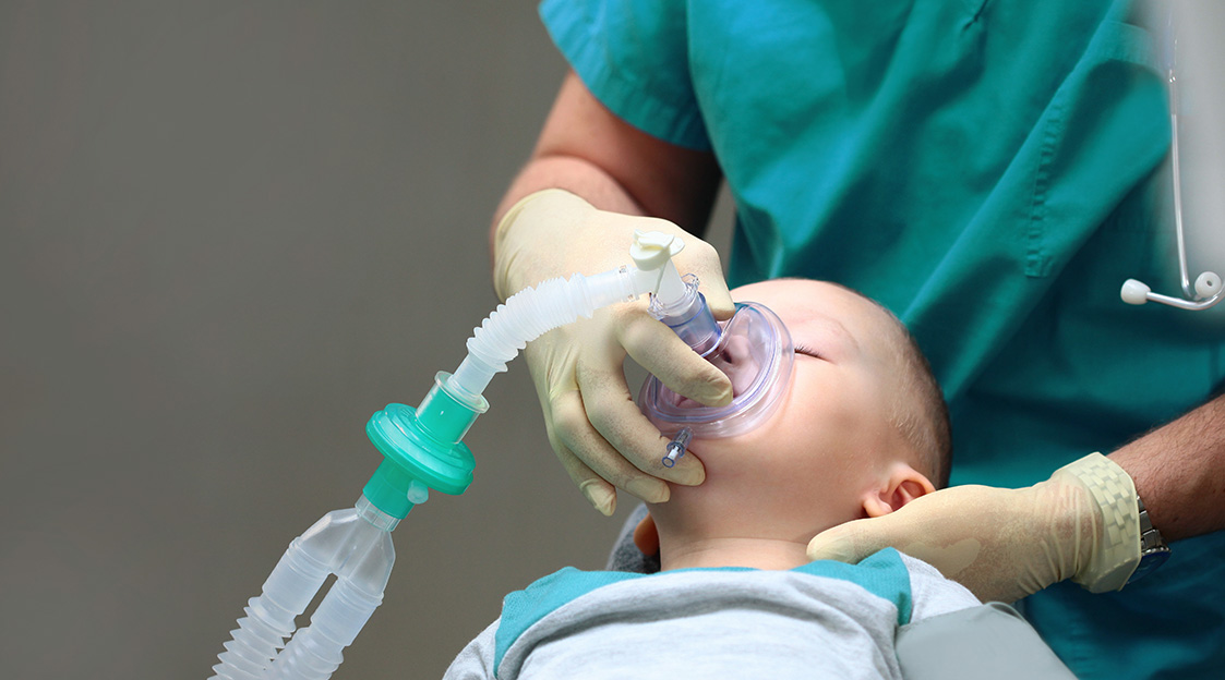 anesthesiologist places a respiratory apparatus over a child's mouth
