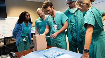 A group of residents stand around a training device