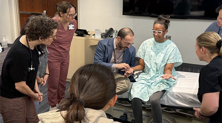A group of medical faculty and residents at Northwestern Feinberg School of Medicine participating in a Bedside Excellence Development Series (BEDS) session, gathered around a patient bed for a clinical teaching demonstration.