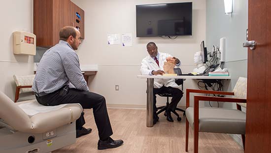 A physician refers to a model of the brain for a patient sitting across the exam room.