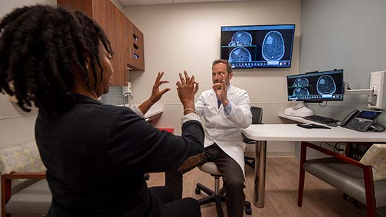 A patient mirrors a doctor pinching their pointer fingers and thumbs together for a test.