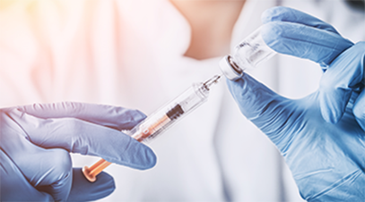 a pair of gloved hands extracting medication from a vial with a syringe