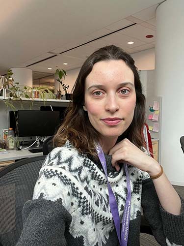 Danielle in a gray and white sweater posing at her desk