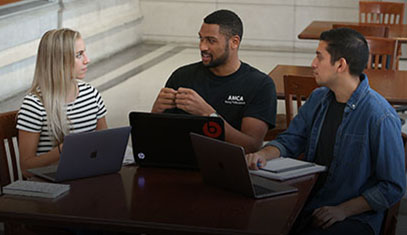 Three students around a table discussing