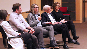 A panel sitting in front of an auditorium talking about epidemiology.