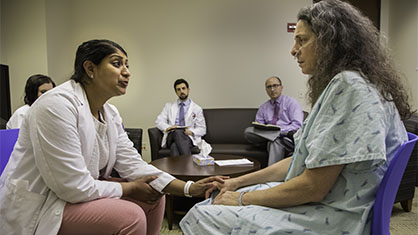 An instructor practices a difficult conversation with a patient, placing a hand on theirs.