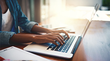 A closeup of someone's hands typing on a laptop