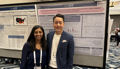 A resident posing in front of her research poster
