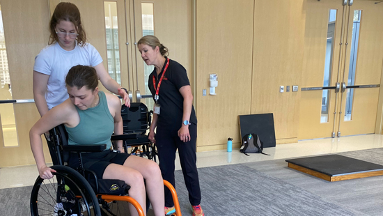 Two clinicians at Shirley Ryan AbilityLab working with a client in a wheelchair