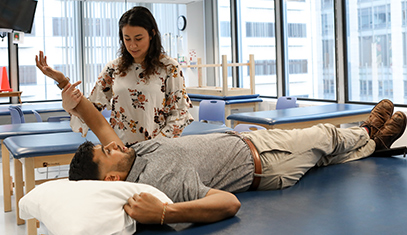 A therapist moves back the arm of a person lying on a mat table