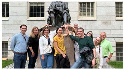 Image of a group of people at the foot of the John Harvard statue