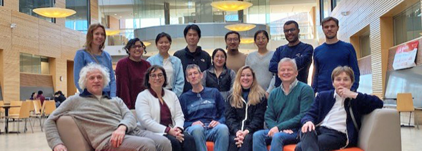 Six people sitting in couch and eigh standing behind couch