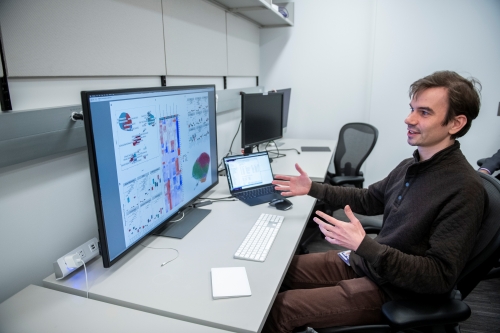 researcher pointing to data displayed on a monitor